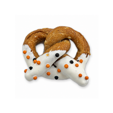 Halloween yogurt-dipped dog pretzel with white icing and orange and black sprinkles